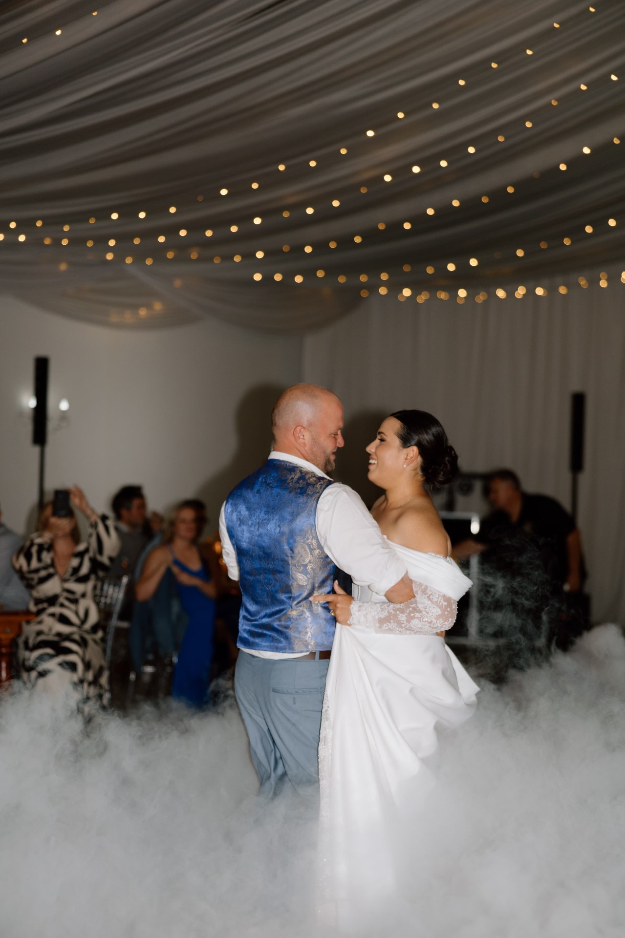 Bride and groom dancing on low-lying dry ice clouds in luxury ballroom